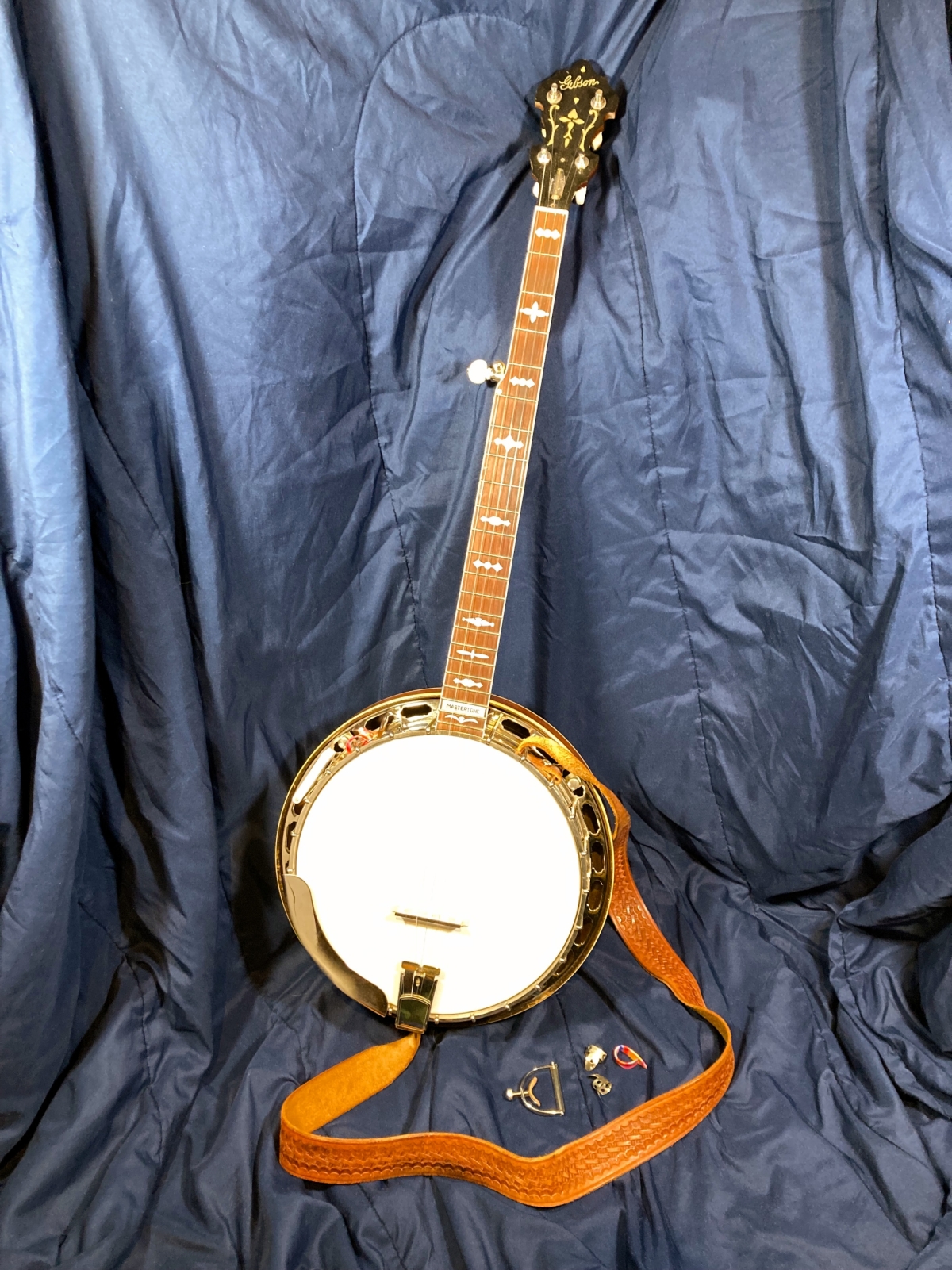 A Gibson banjo leaning against a silky blue background